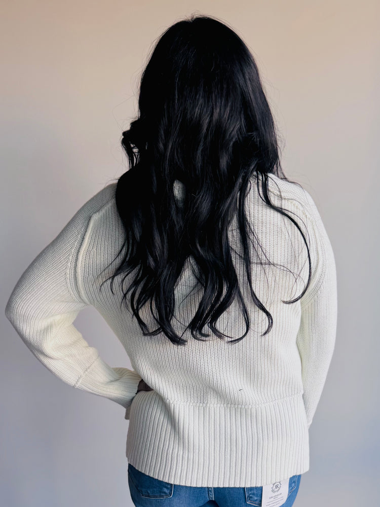 Back view of ivory knit sweater with exposed seams and casual silhouette