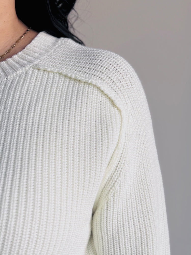 Close-up of ribbed knit texture and raglan sleeve detail on ivory sweater