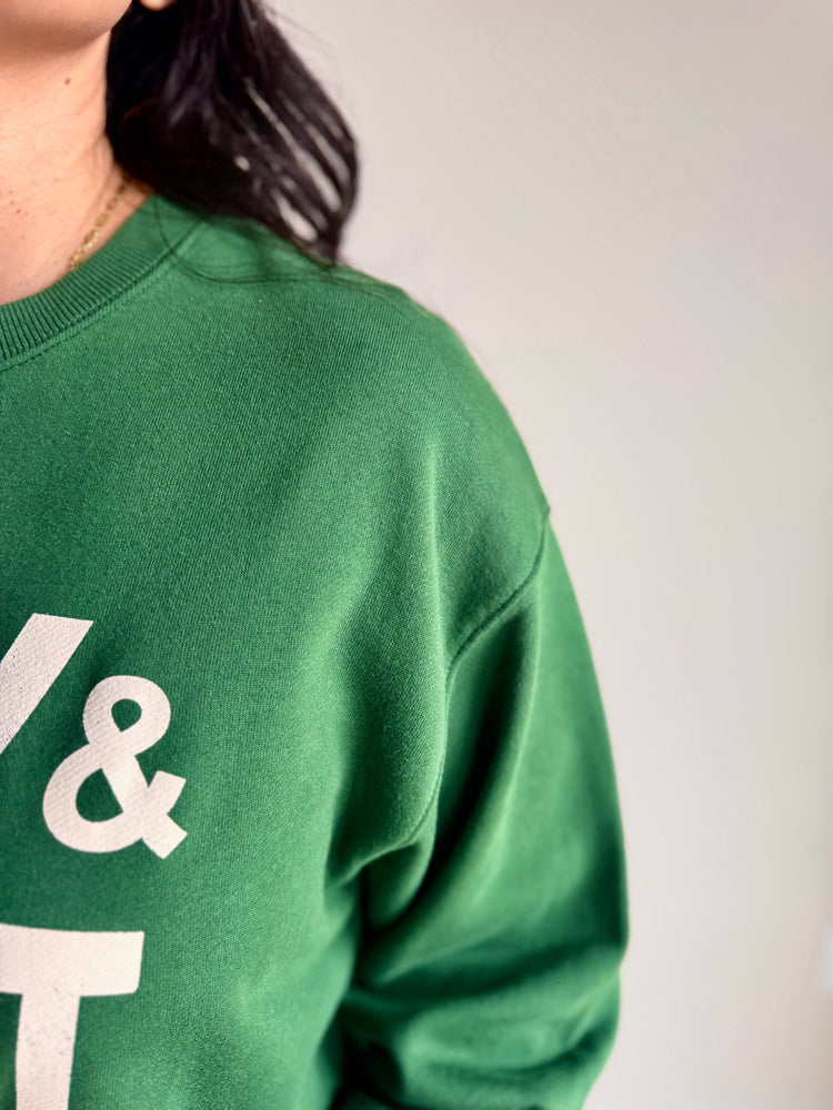 Close-up of Merry & Bright graphic print and ribbed neckline on green crewneck