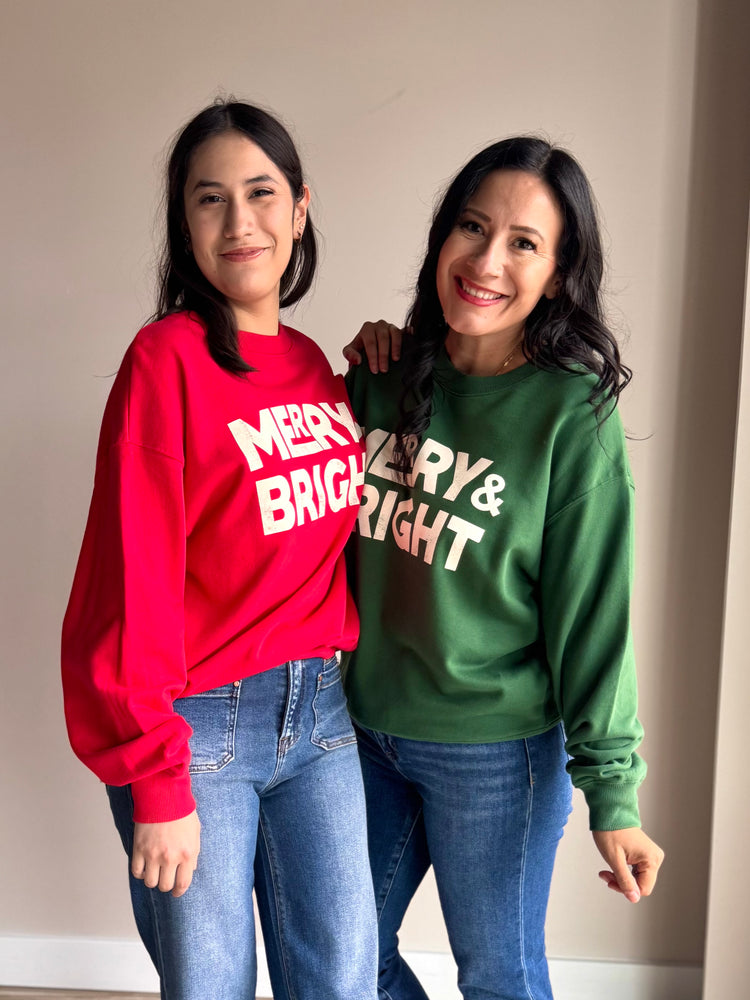 Folded view of green and white crewneck showing soft fleece fabric and festive lettering