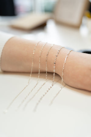 Customer showing stacked welded bracelets after permanent jewelry appointment in Puyallup