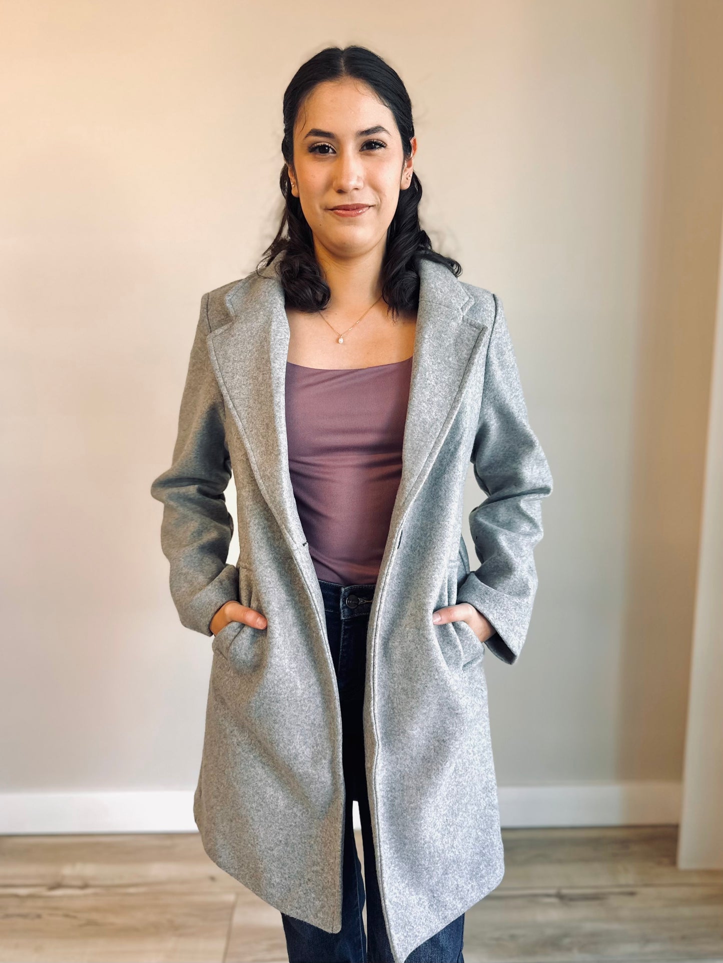 Front view of a women’s long peacoat in light grey with lapel collar and single-button closure, styled for fall outerwear.