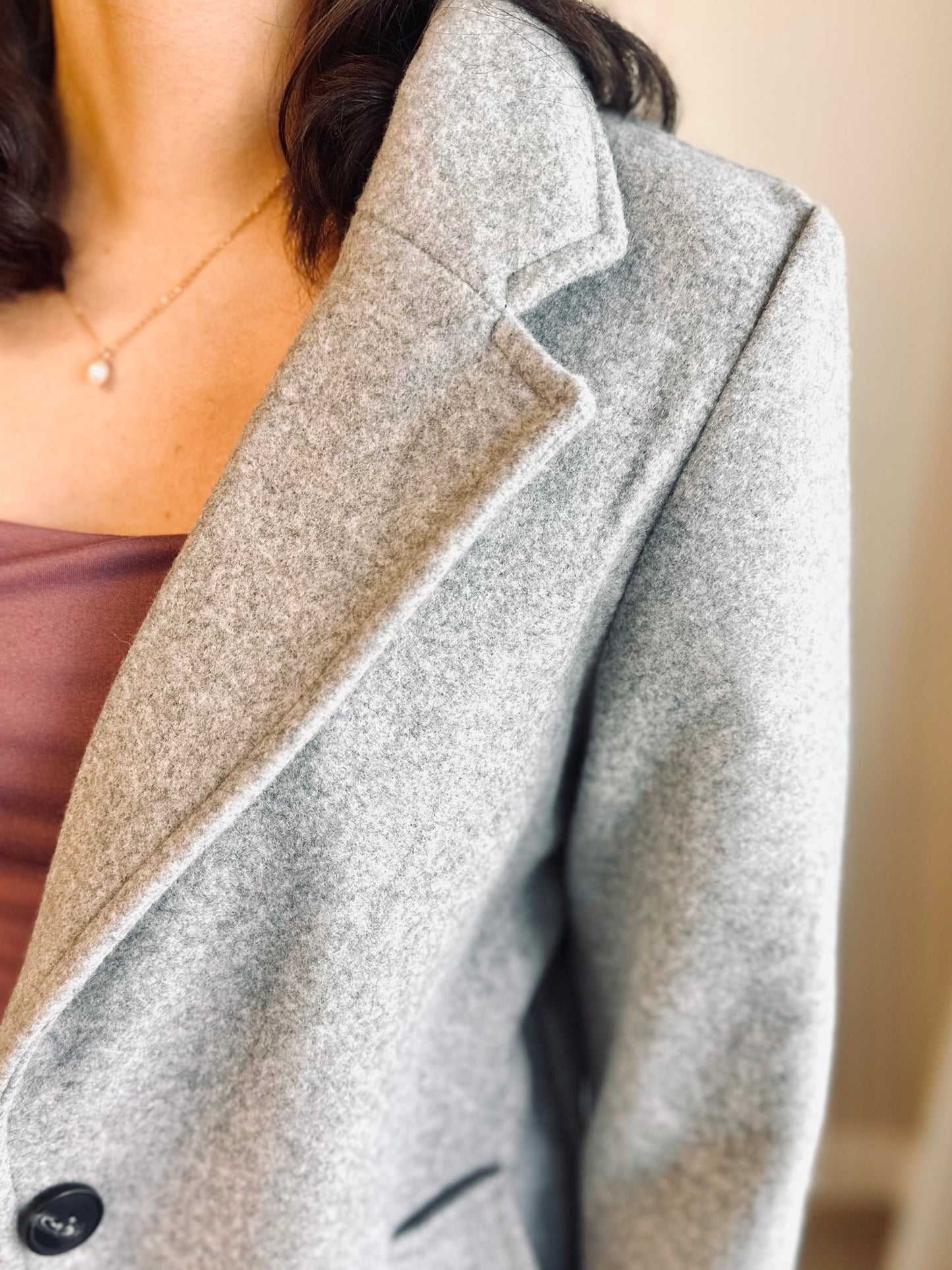 Back view of a light grey women’s long peacoat showing clean lines and mid-thigh length, ideal for layering.